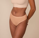 Side view of Victoria modeling the Cloud Cotton Highwaist Thong in Dune. The smooth, stretchy cotton-modal fabric contours comfortably around the hips.