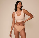 Victoria standing confidently in a front-facing pose wearing the Cloud Cotton Highwaist Thong in Dune, paired with the Bliss Bralette in Beige. The high-waisted thong enhances the natural waistline.