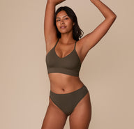 Victoria wearing the Cloud Cotton Highwaist Thong in Olive with the matching Triangle Bralette, standing with arms raised.