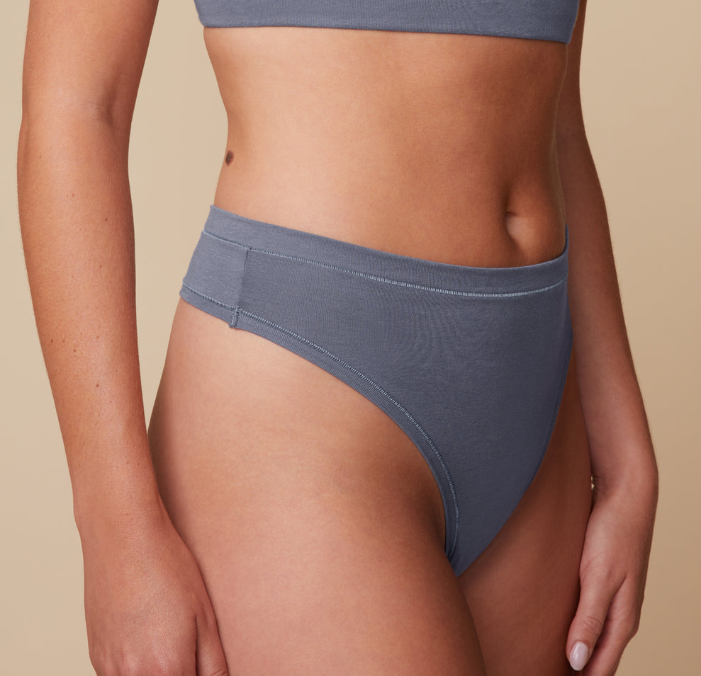 Close-up side view of Megan wearing the Cloud Cotton Highwaist Thong in Slate. The soft waistband and flat seams are visible, emphasizing the clean finish and all-day comfort.