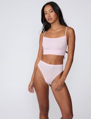 On a clean studio backdrop, a full-body view shows a model wearing the Cloud Cotton Highwaist Thong in Primrose with the matching Cloud Cotton Thin Strap Bralette, highlighting the high-rise waistband and soft cotton modal fabric.