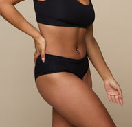 Three quarter angle of Jade in the Cloud Cotton Hiphugger in Black. The comfortable leg openings and minimal seams are emphasized.