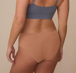 Back view of model Sonnie wearing the Cloud Cotton Hiphugger in Dune. The image highlights the full back coverage and comfortable waistband that stays in place without digging.