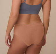 Back view of model Sonnie wearing the Cloud Cotton Hiphugger in Dune. The image highlights the full back coverage and comfortable waistband that stays in place without digging.