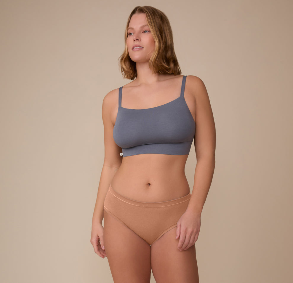 Model Sonnie stands in a relaxed pose wearing the Cloud Cotton Hiphugger in Dune and the Cloud Cotton Thin Strap Bralette. The image shows the underwear’s natural fit and breathable cotton modal blend.