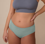 Model Sonnie wears the Cloud Cotton Hiphugger in Seaglass, shown from the front with one hand on her hip. The mid-rise cut and soft, stretch cotton modal fabric offer full front coverage and a smooth fit. sizing: Sonnie wears size Large