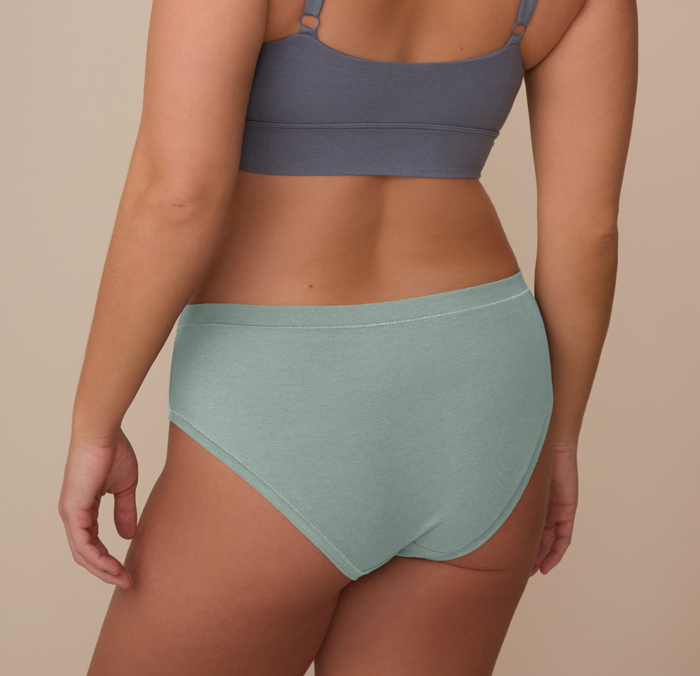 Back view of model Sonnie wearing the Cloud Cotton Hiphugger in Seaglass. The image highlights the full back coverage and comfortable waistband that stays in place without digging.