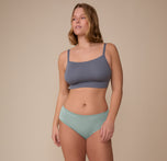 Model Sonnie stands in a relaxed pose wearing the Cloud Cotton Hiphugger in Seaglass and the Cloud Cotton Thin Strap Bralette. The image shows the underwear’s natural fit and breathable cotton modal blend.