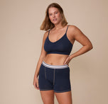Full-body image of Sonnie wearing the matching Cloud Cotton Triangle Bralette and Retro Boxer Brief in Midnight. Her pose shows off the coordinated lounge-ready set with bold waistband detail.