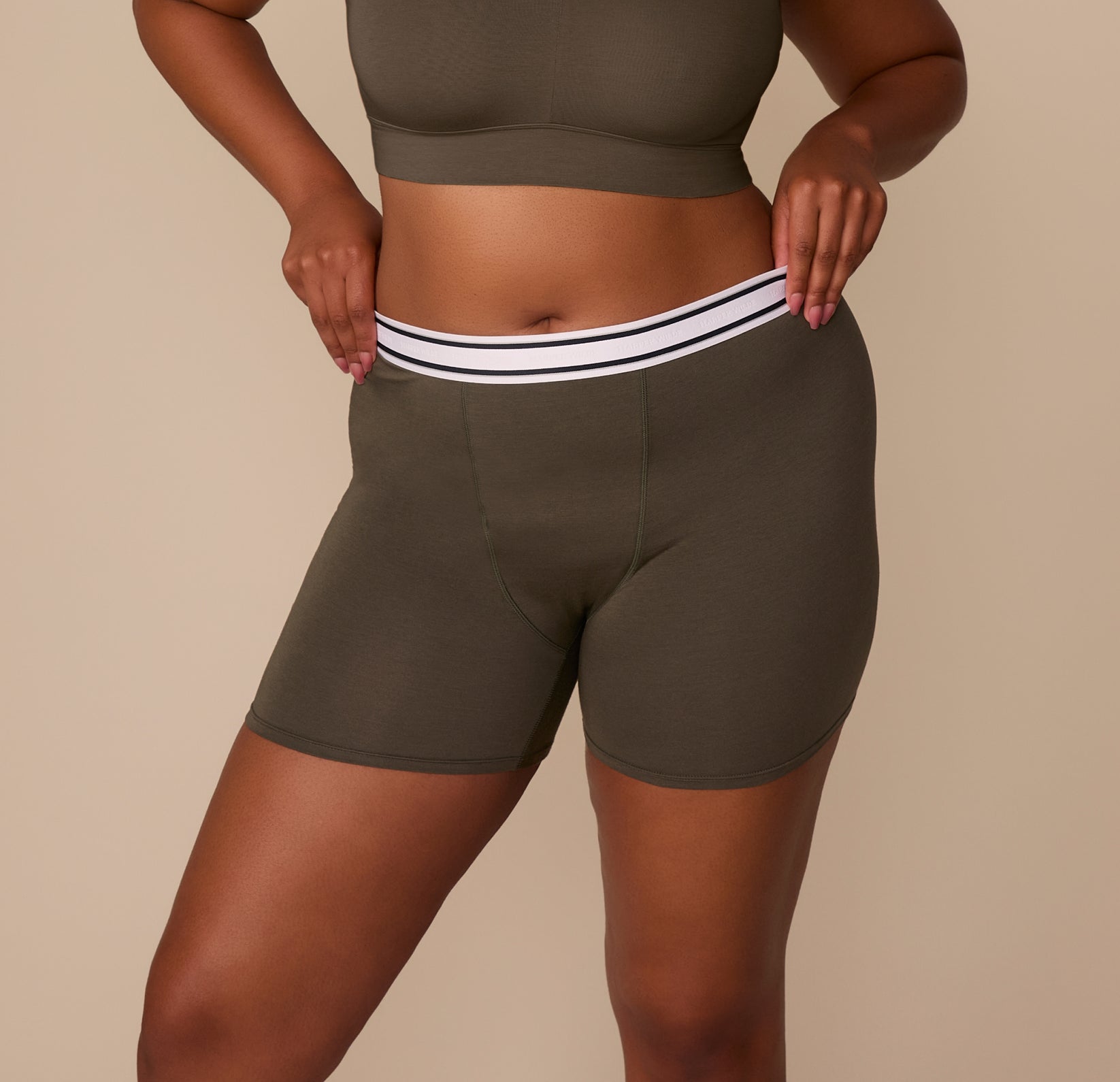 Close-up of Zarria wearing the Cloud Cotton Retro Boxer Brief in Olive, highlighting the mid-thigh length and branded elastic waistband. sizing: Zarria wears size XL