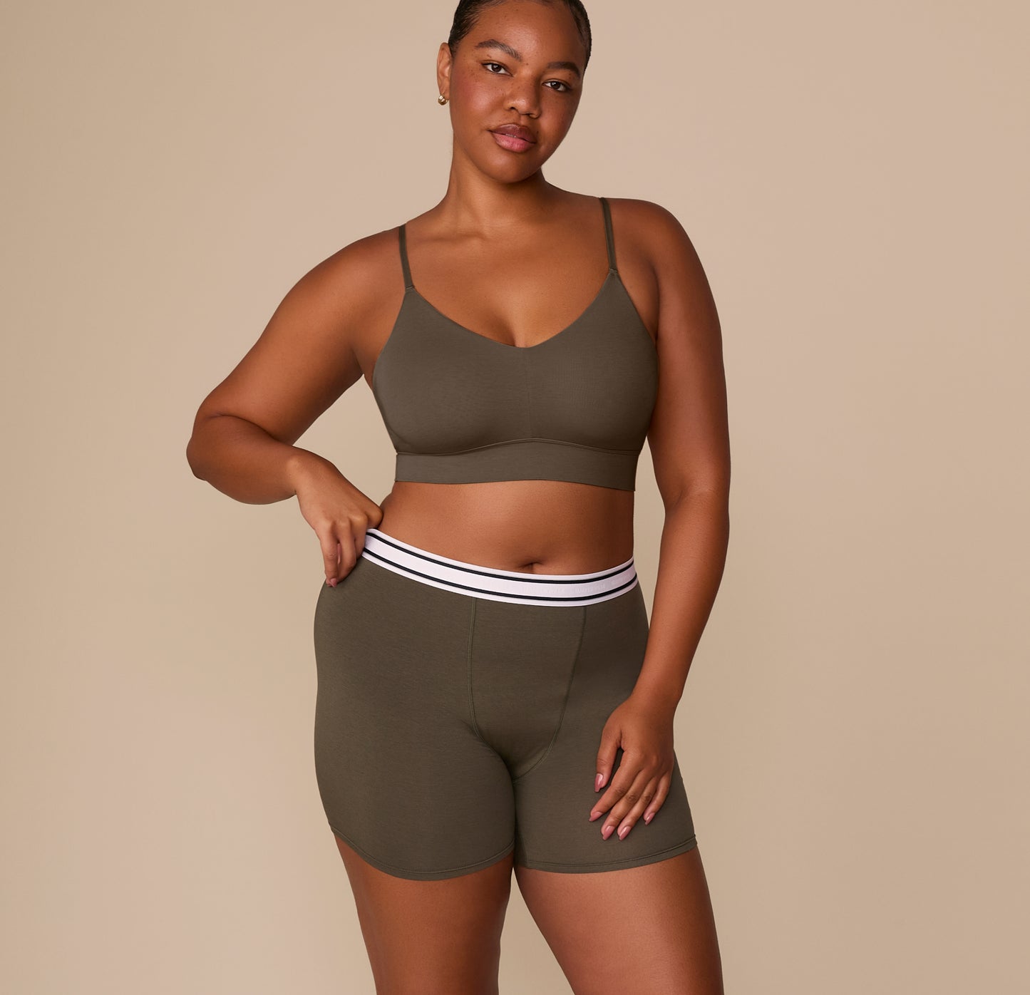 Zarria wearing the Cloud Cotton Retro Boxer Brief in Olive with the Cloud Cotton Triangle Bralette, standing with one hand resting on the waistband.