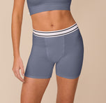 Model Freya wears the Cloud Cotton Boxer Brief in Slate, shown from the front. The image highlights the mid-thigh length, double-striped waistband, and soft cotton modal fabric. sizing: Freya wears size Small