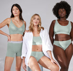 Anna, Megan, and Akesha pose together in relaxed stances. Anna models the Cloud Cotton Logo Boxer Brief in Seaglass. The versatility of the color Seaglass is emphasized. 