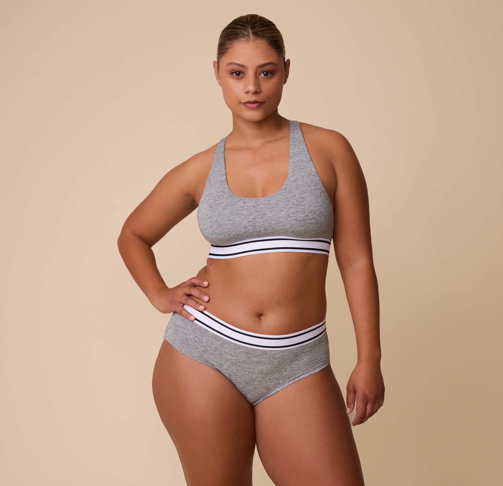 A full-length shot of India in the Cloud Cotton Retro Racerback Bralette in Heather Charcoal, paired with the matching Cloud Cotton Hiphugger in Heather Charcoal.