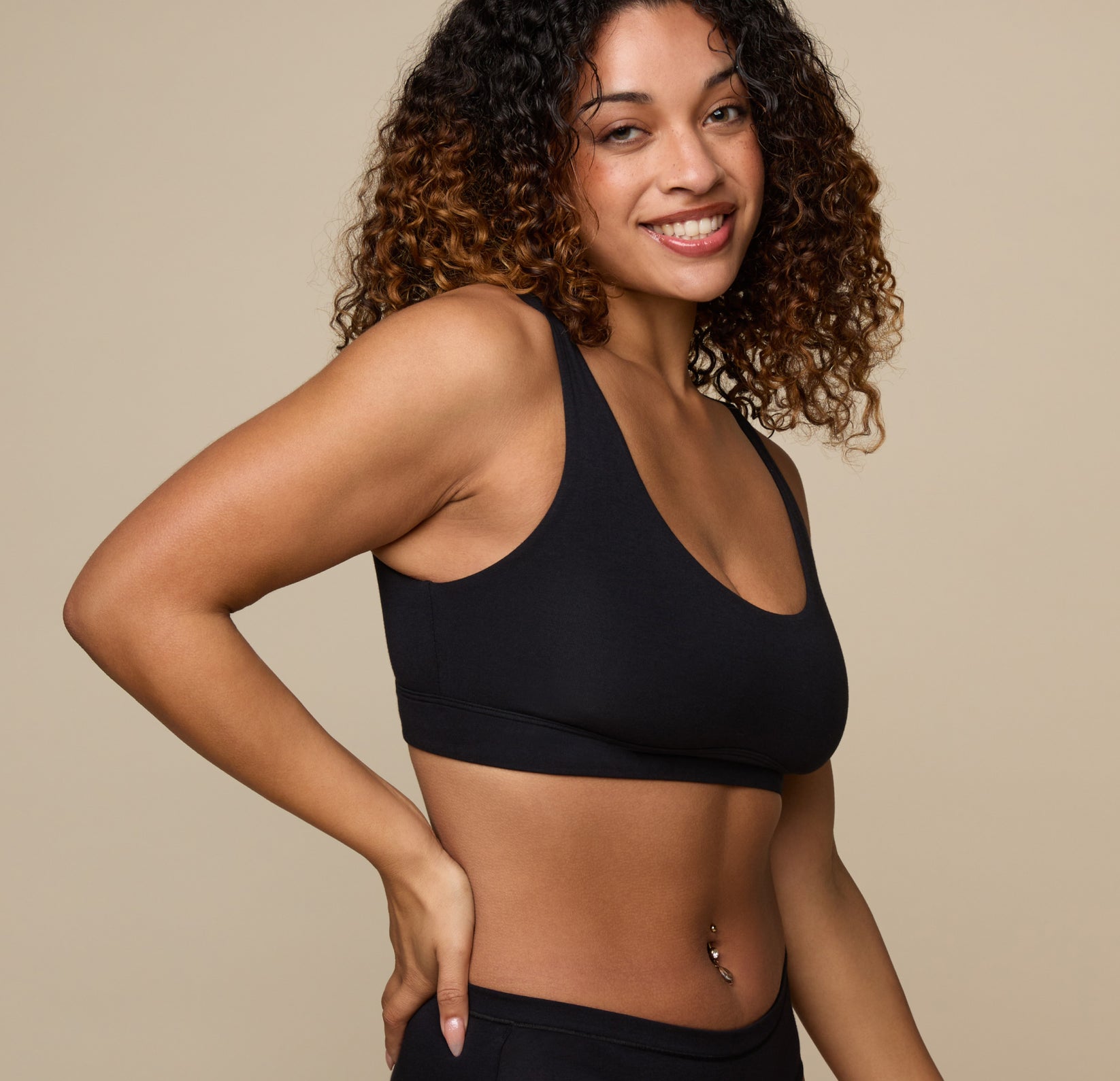 Side profile of Jade smiling in the Cloud Cotton Scoop Bralette in Black. The wide straps and full coverage are visible, emphasizing comfort and soft structure.
