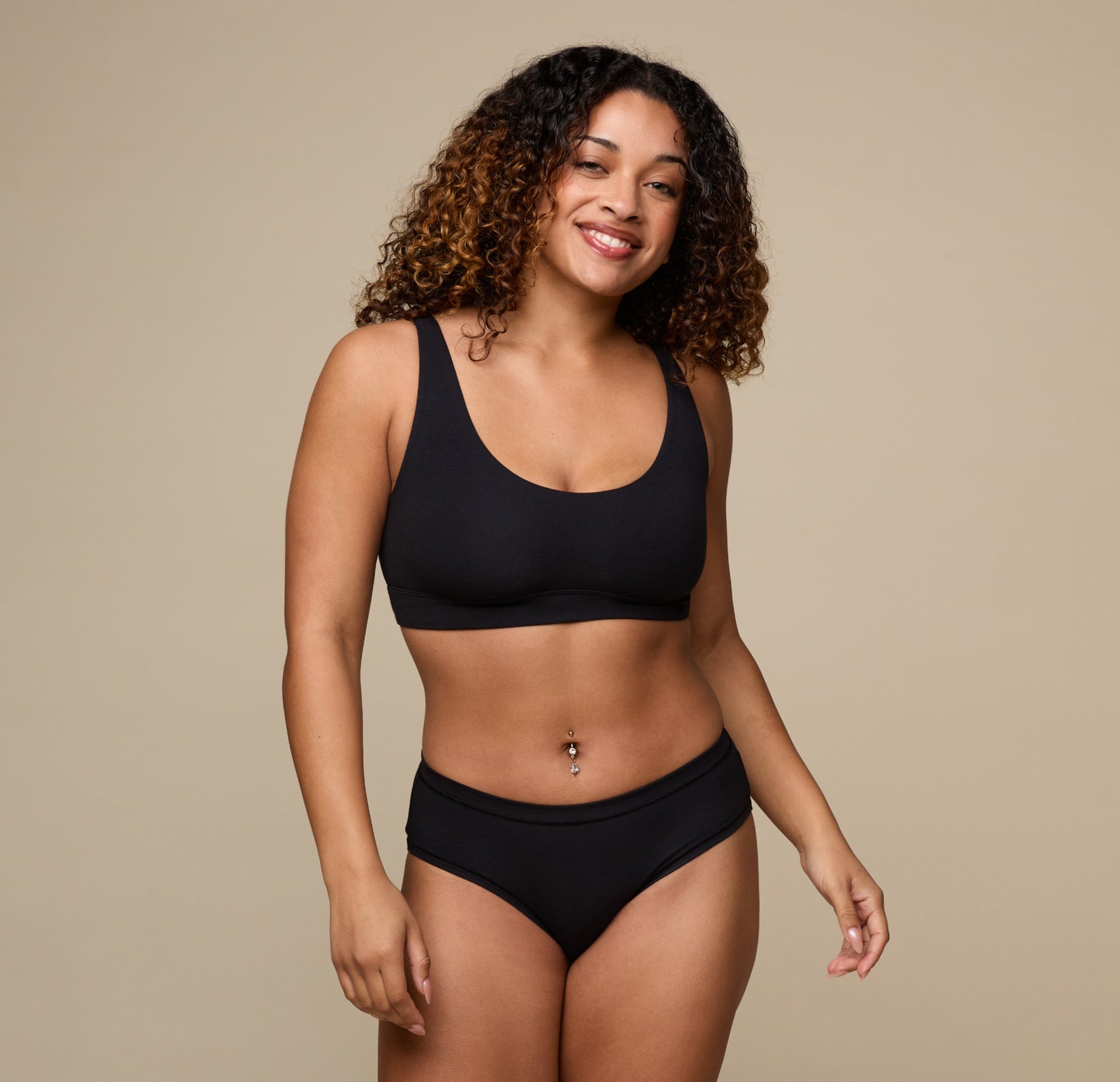 Jade stands relaxed, smiling in the Cloud Cotton Scoop Bralette in Black and the matching Cloud Cotton Hiphugger. The set highlights softness and comfort for everyday lounging.