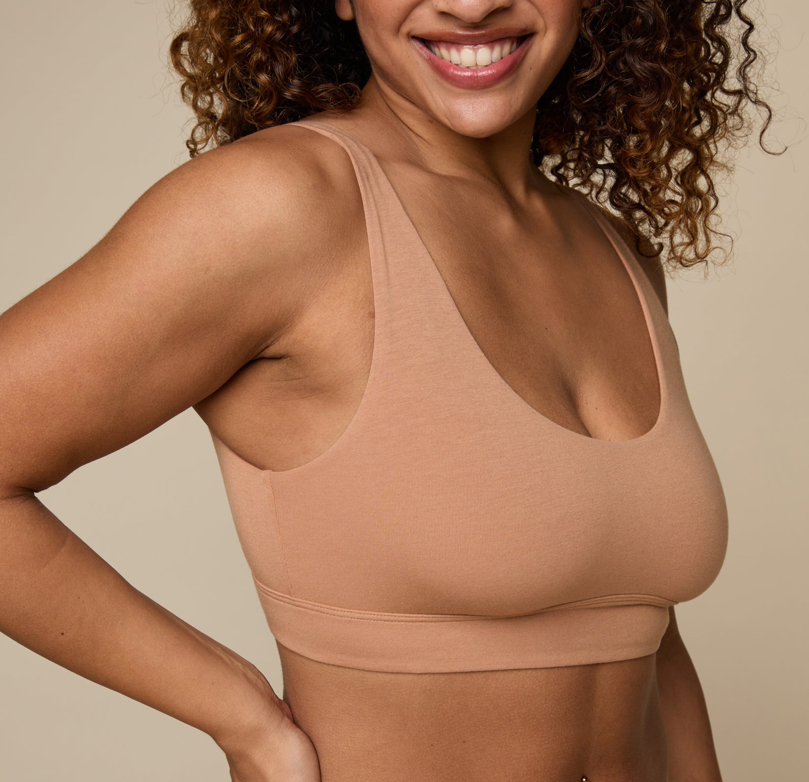 Close up view of Jade wearing the Cloud Cotton Scoop in Dune. The scoop neckline, wide underband, and ultra-soft cotton modal fabric are emphasized. 