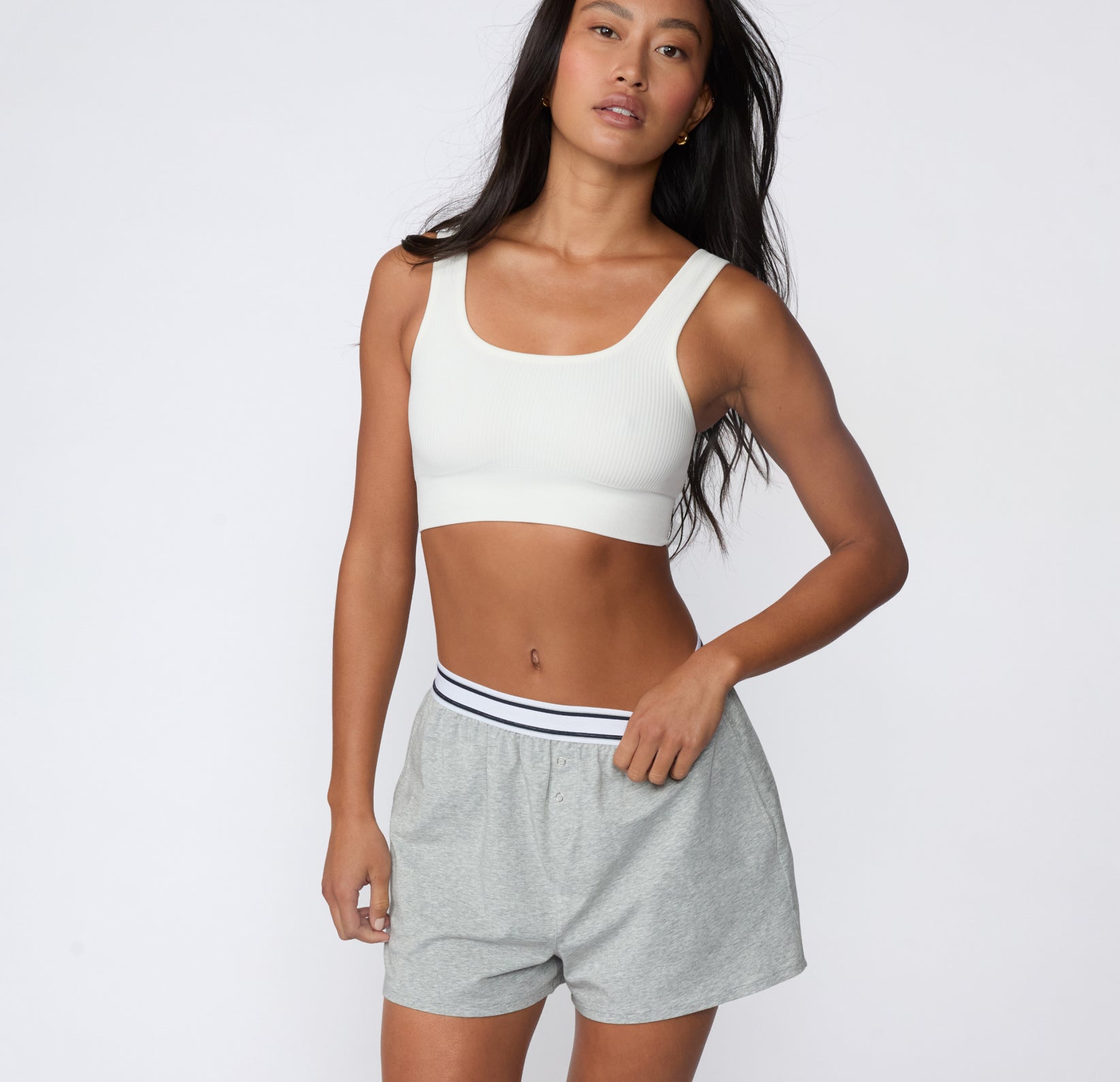 On a white studio backdrop, a model stands facing forward in the CloudCotton Short in Heather Grey, highlighting the mid-rise elastic waistband and easy, lounge-ready silhouette.