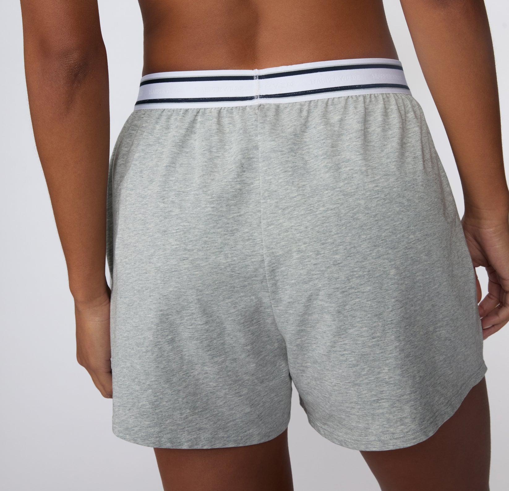 On a white studio backdrop, a back view of the CloudCotton Short in Heather Grey shows the smooth cotton fabric and full coverage through the seat.