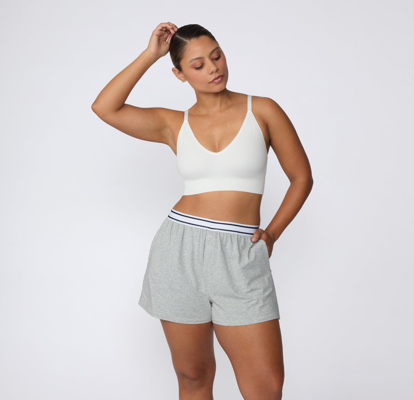 On a white studio backdrop, a model wears the CloudCotton Short in Heather Grey with one hand in the side pocket, showing the relaxed leg opening and breathable cotton feel.