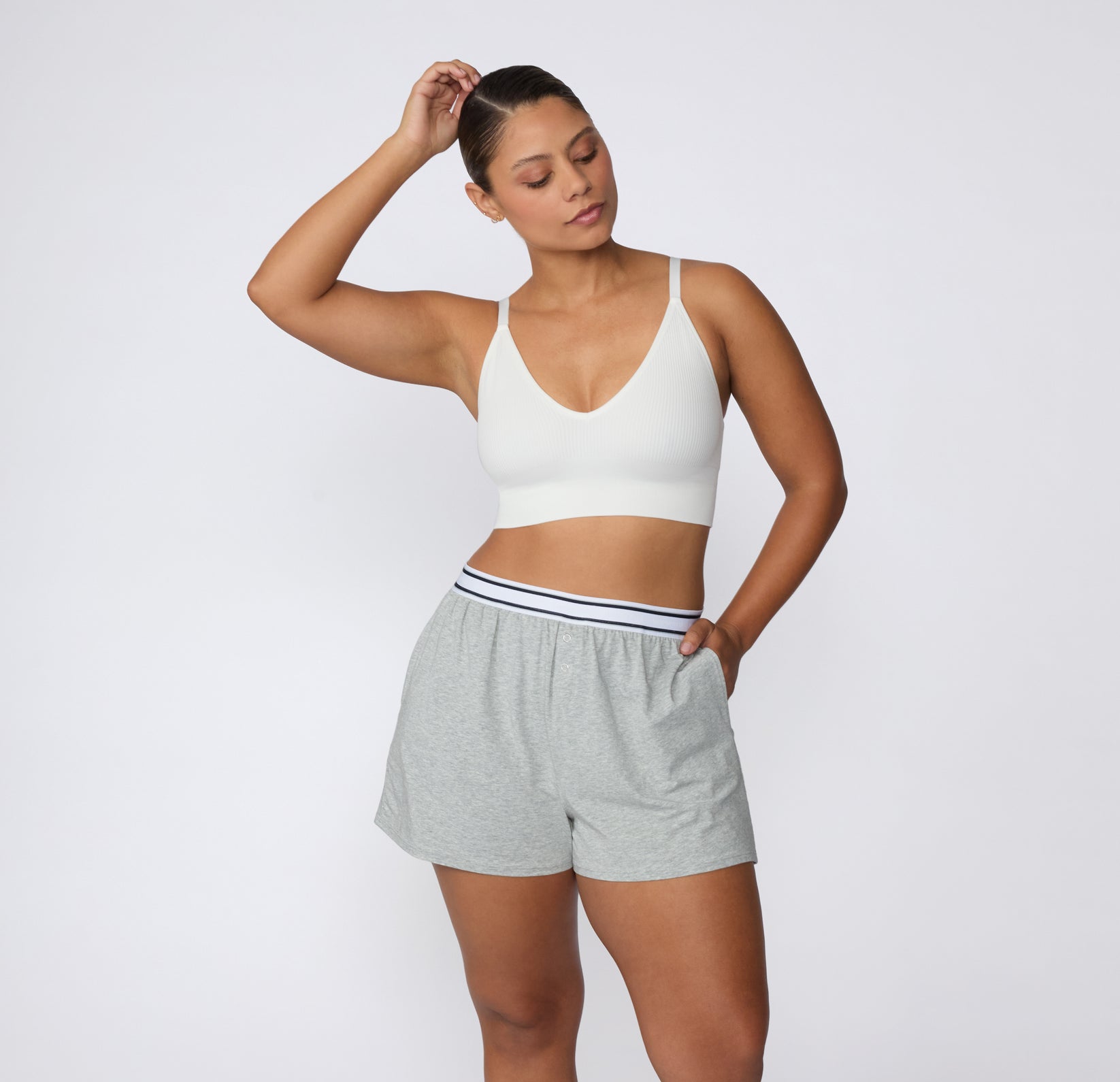 On a white studio backdrop, a model wears the CloudCotton Short in Heather Grey with one hand in the side pocket, showing the relaxed leg opening and breathable cotton feel.