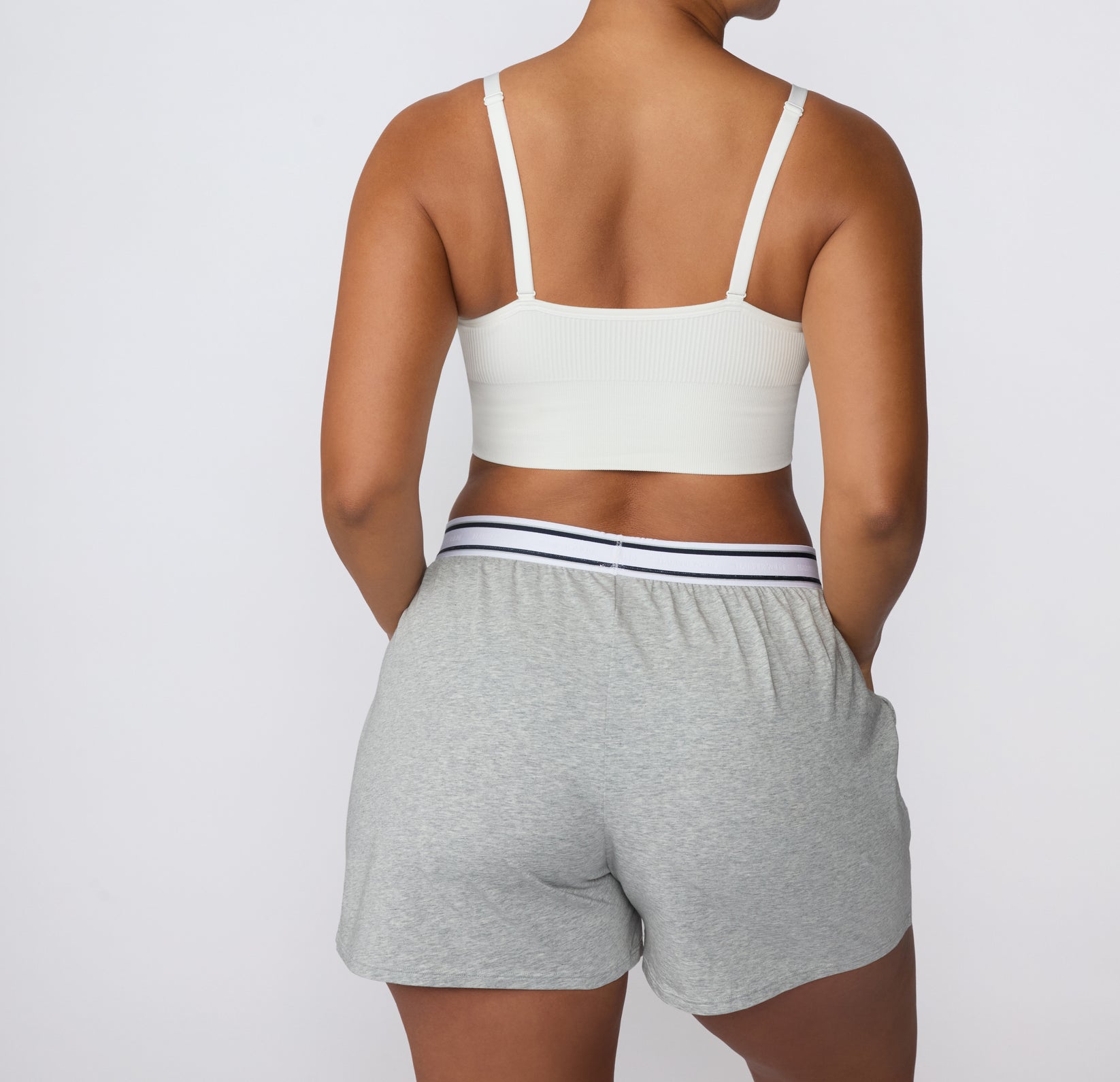 On a white studio backdrop, a back view of the CloudCotton Short in Heather Grey highlights the elastic waistband and soft cotton construction designed for everyday comfort.