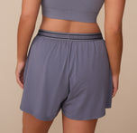 Back view of Sonnie in the Cloud Cotton Sleep Short in Slate. The elastic waistband sits comfortably at the mid-rise, with Harper Wilde branding visible around the band.