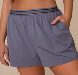Detailed front view of the Cloud Cotton Sleep Short in Slate worn by Sonnie. The image focuses on the branded waistband, functional side pocket, and button fly accents.