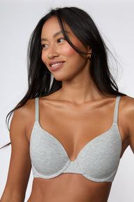 On a white studio backdrop, Amber wears the Cloud Cotton T-Shirt Bra in Heather Grey in a close-up front view, highlighting the cotton modal fabric, smooth cup shape, and front-adjusting straps.