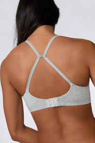 On a white studio backdrop, Amber is shown from the back wearing the Cloud Cotton T-Shirt Bra in Heather Grey, highlighting the convertible J-hook straps worn in a racerback position and the hook-and-eye back closure.