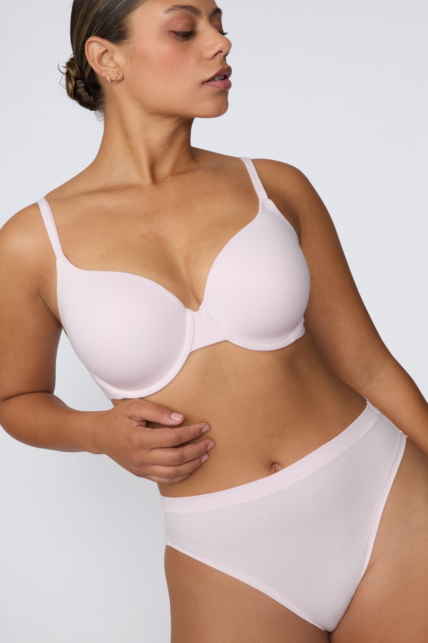 On a white studio backdrop, India wears the Cloud Cotton T-Shirt Bra in Primrose with the matching Cloud Cotton brief, shown in a three-quarter front view highlighting the smooth cups, adjustable straps, and everyday silhouette.