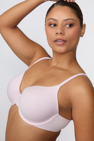 On a white studio backdrop, India wears the Cloud Cotton T-Shirt Bra in Primrose in a close-up angled view, emphasizing the lightly lined cups, clean neckline, and low-profile cotton modal band.