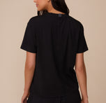 Back view of Marcela wearing the Cloud Cotton T-Shirt in Black. The shirt features a center seam detail and a relaxed fit through the shoulders and torso.