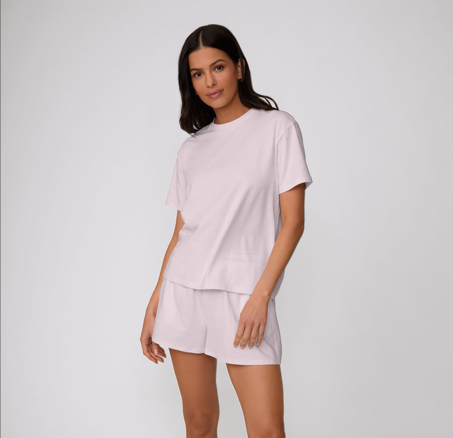 On a clean studio backdrop, a full-body view shows a model wearing the Cloud Cotton Tee in Primrose with matching lounge shorts, highlighting the relaxed fit and soft cotton modal fabric.