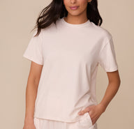 Marcela wearing the Cloud Cotton T-Shirt in Quartz. She stands with one hand in her pocket, showing off the relaxed, everyday fit and classic crew neckline of the tee. sizing: Marcela wears size XS