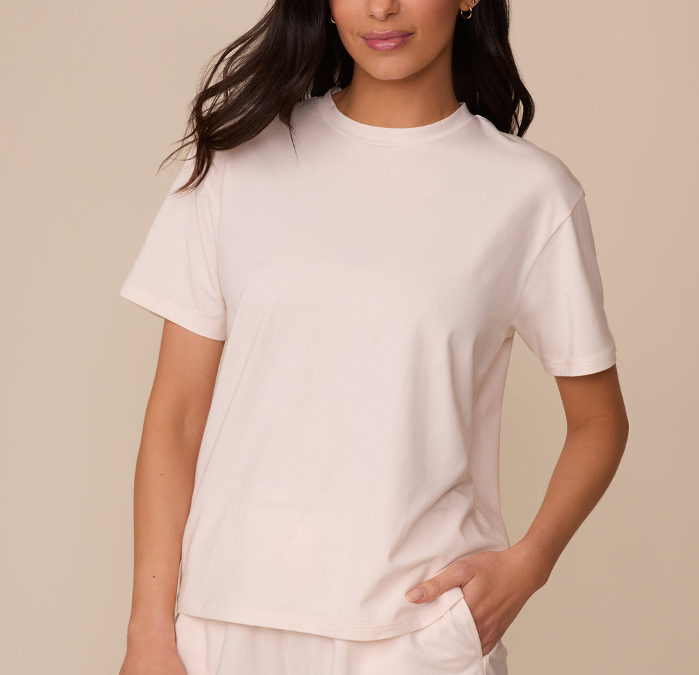 Marcela wearing the Cloud Cotton T-Shirt in Quartz. She stands with one hand in her pocket, showing off the relaxed, everyday fit and classic crew neckline of the tee. sizing: Marcela wears size XS