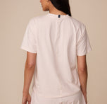 Back view of Marcela wearing the Cloud Cotton T-Shirt in Quartz. The shirt features a center seam detail and a relaxed fit through the shoulders and torso.