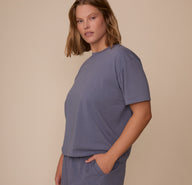 Side profile of Sonnie wearing the Cloud Cotton T-Shirt in Slate. She has one hand in her pocket, emphasizing the tee’s relaxed drape and comfortable, roomy shape.