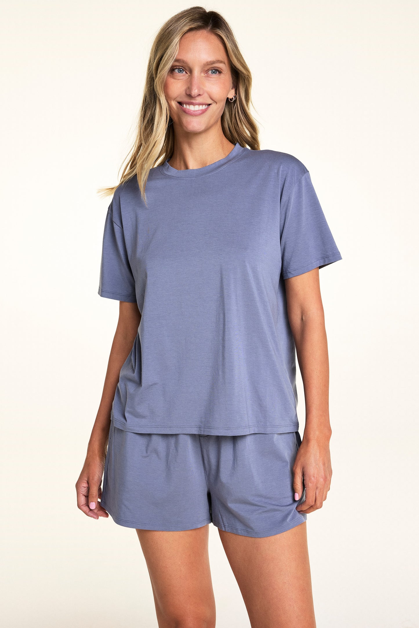 In a softly lit studio, Meagan wears the Cloud Cotton Tee and Cloud Cotton Short in Slate. The relaxed-fit tee features short sleeves and soft cotton modal fabric, paired with matching lounge shorts designed for easy everyday comfort.