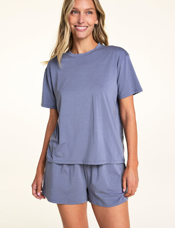 In a softly lit studio, Meagan wears the Cloud Cotton Tee and Cloud Cotton Short in Slate. The relaxed-fit tee features short sleeves and soft cotton modal fabric, paired with matching lounge shorts designed for easy everyday comfort.