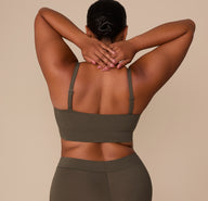 Back view of Zarria in the Cloud Cotton Thin Strap Bralette in Olive, arms raised to show the adjustable straps and longline band.