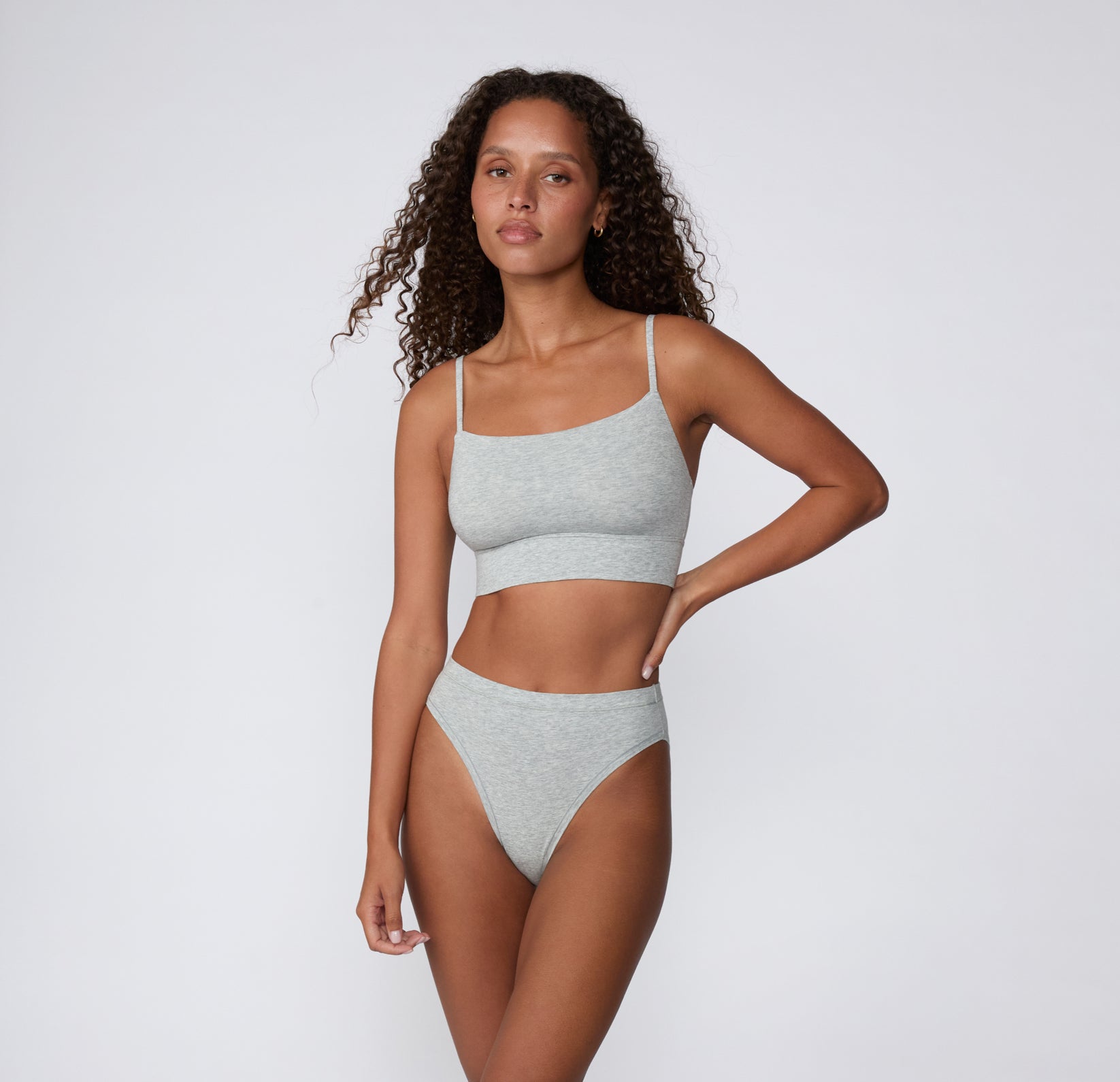 Full-body view on a light studio backdrop of the Cloud Cotton Thin Strap Bralette in Light Heather Grey, paired with matching underwear, showing the longline underband and thin adjustable straps.