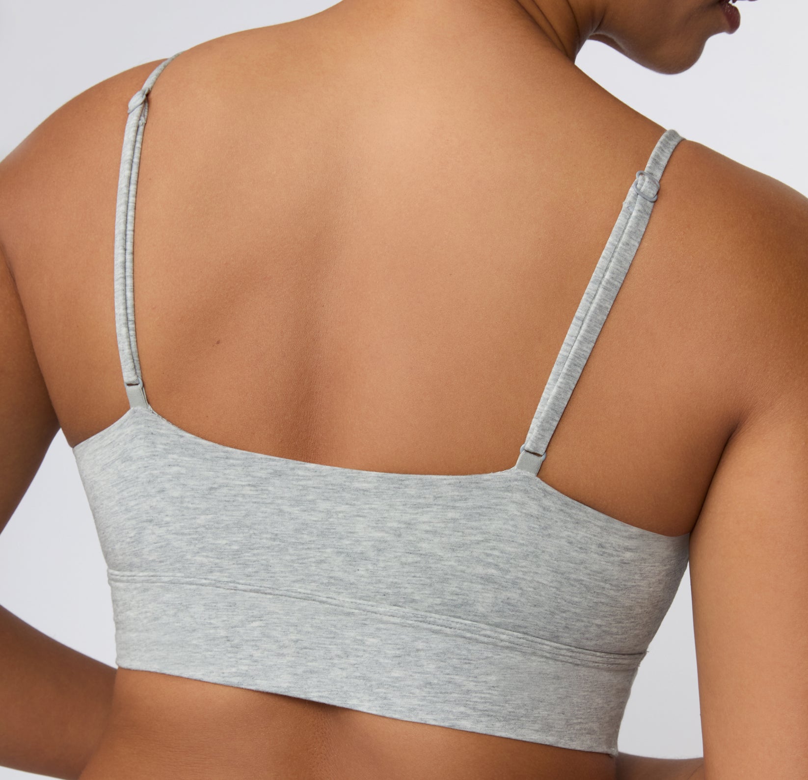 Back view on a light studio backdrop of the Cloud Cotton Thin Strap Bralette in Light Heather Grey, highlighting the straight back band and back-adjusting thin straps.