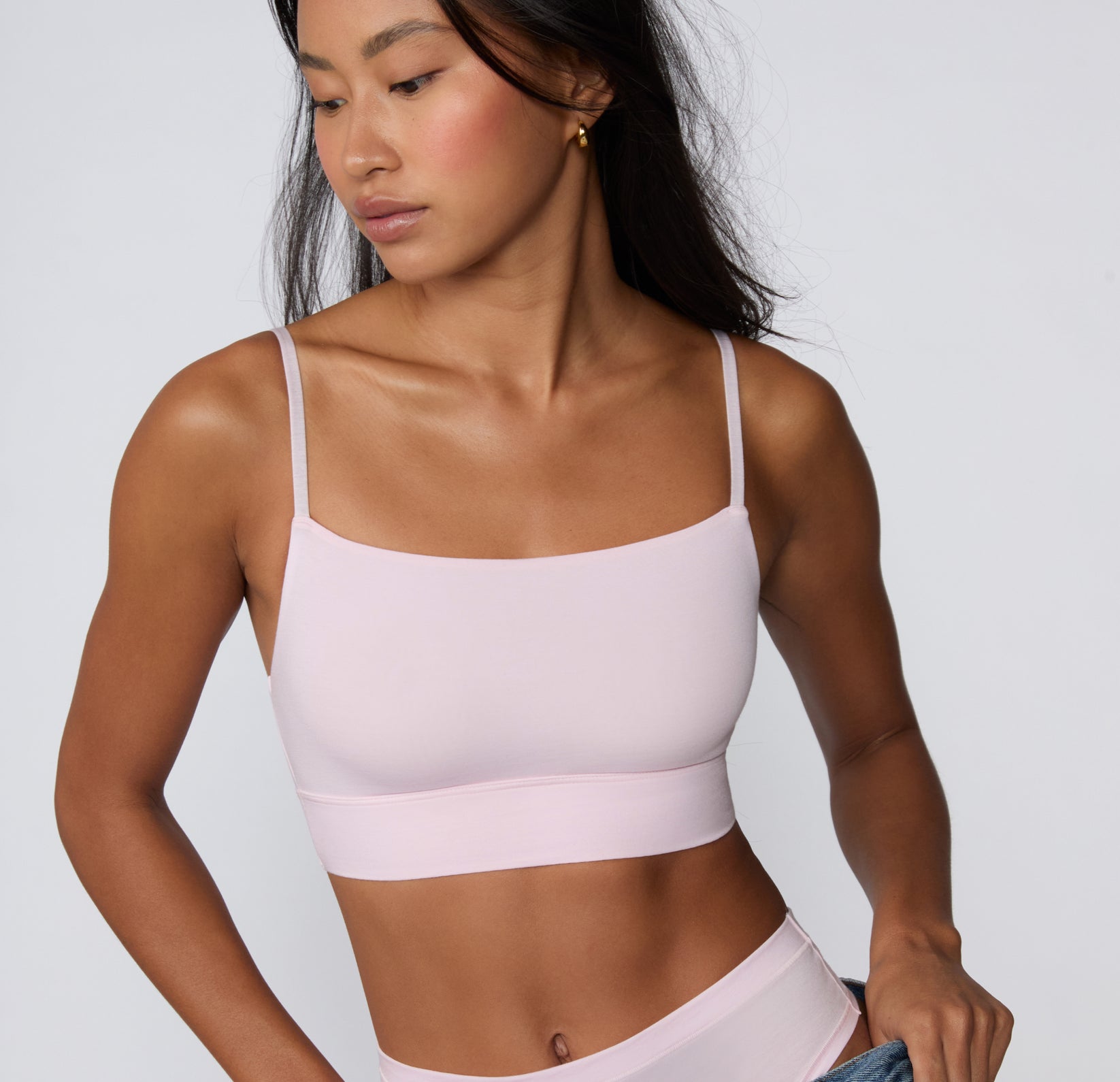 On a clean studio backdrop, a model wears the Cloud Cotton Thin Strap Bralette in Primrose, showing the soft square neckline, thin adjustable straps, and longline cotton modal band from a front-facing angle. sizing: Amber wears size XS