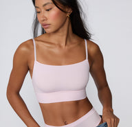 On a clean studio backdrop, a model wears the Cloud Cotton Thin Strap Bralette in Primrose, showing the soft square neckline, thin adjustable straps, and longline cotton modal band from a front-facing angle. sizing: Amber wears size XS