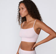 On a clean studio backdrop, a side profile shows a model wearing the Cloud Cotton Thin Strap Bralette in Primrose, highlighting the soft square neckline, thin adjustable straps, and smooth longline cotton modal band.