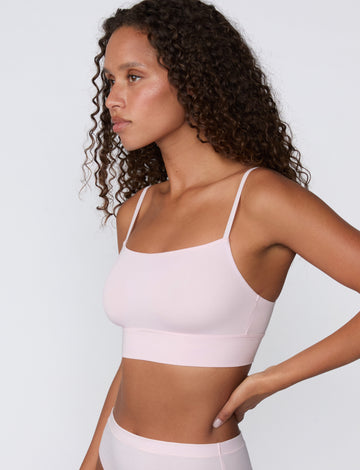On a clean studio backdrop, a side profile shows a model wearing the Cloud Cotton Thin Strap Bralette in Primrose, highlighting the soft square neckline, thin adjustable straps, and smooth longline cotton modal band.