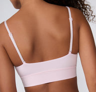 On a clean studio backdrop, a back view shows a model wearing the Cloud Cotton Thin Strap Bralette in Primrose, featuring thin adjustable straps and a smooth, supportive longline band.