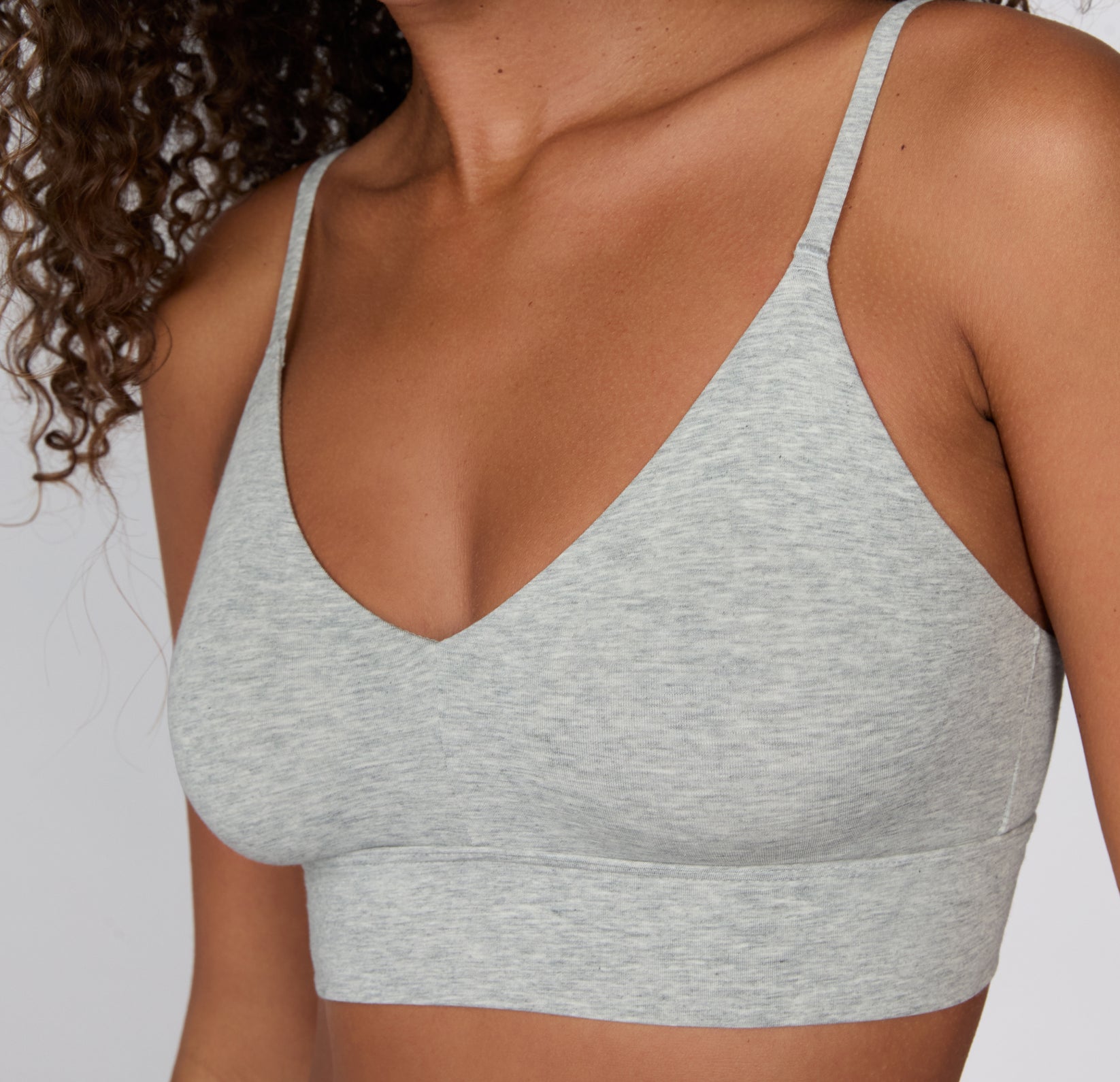 On a white studio background, a close-up shows the Cloud Cotton Triangle Bralette in Heather Grey, highlighting the soft V-neckline, smooth cotton-modal fabric, and clean stitching along the underband.