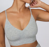 On a clean studio backdrop, a close-up shows the Cloud Cotton Triangle Bralette in Heather Grey, highlighting the soft V-neckline, thin adjustable straps, and smooth cotton-modal fabric.